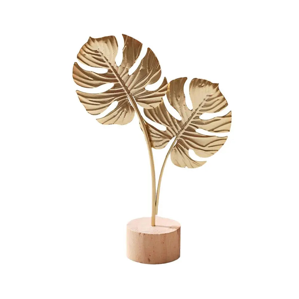 Filigranes Deko-Element mit tropischem Blätterdesign aus Metall auf stabilem Holzsockel – fünf Varianten für einen eleganten Akzent in modernen Wohnräumen.